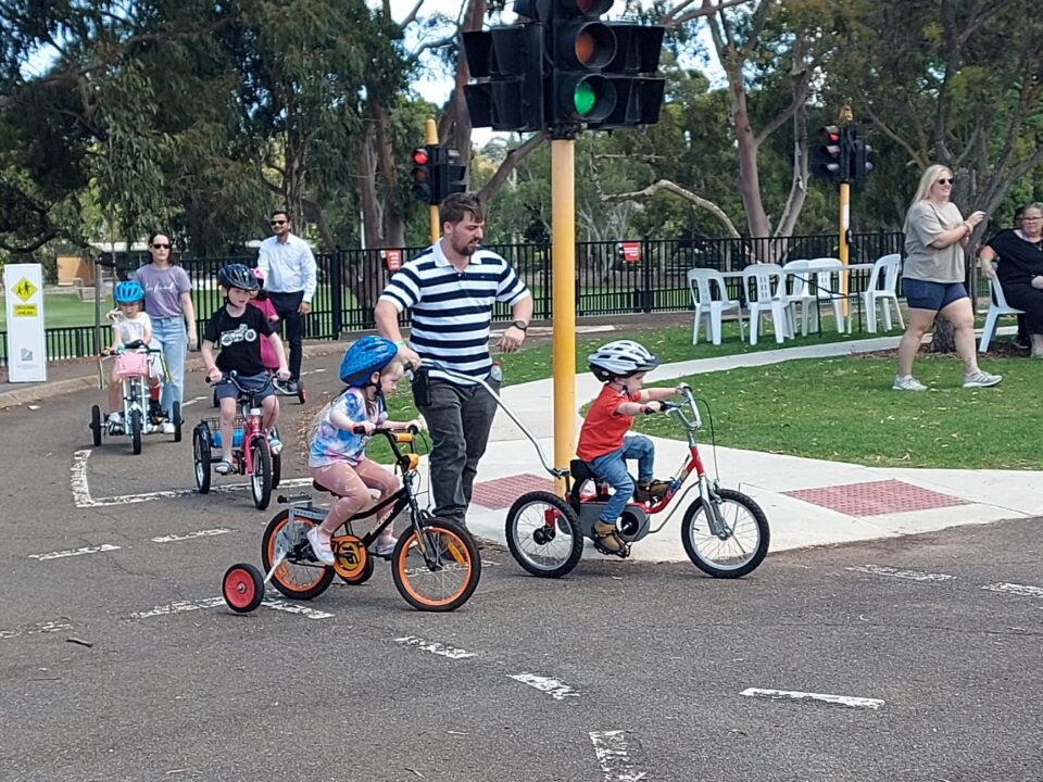 Young trike rider being pushed by his Dad